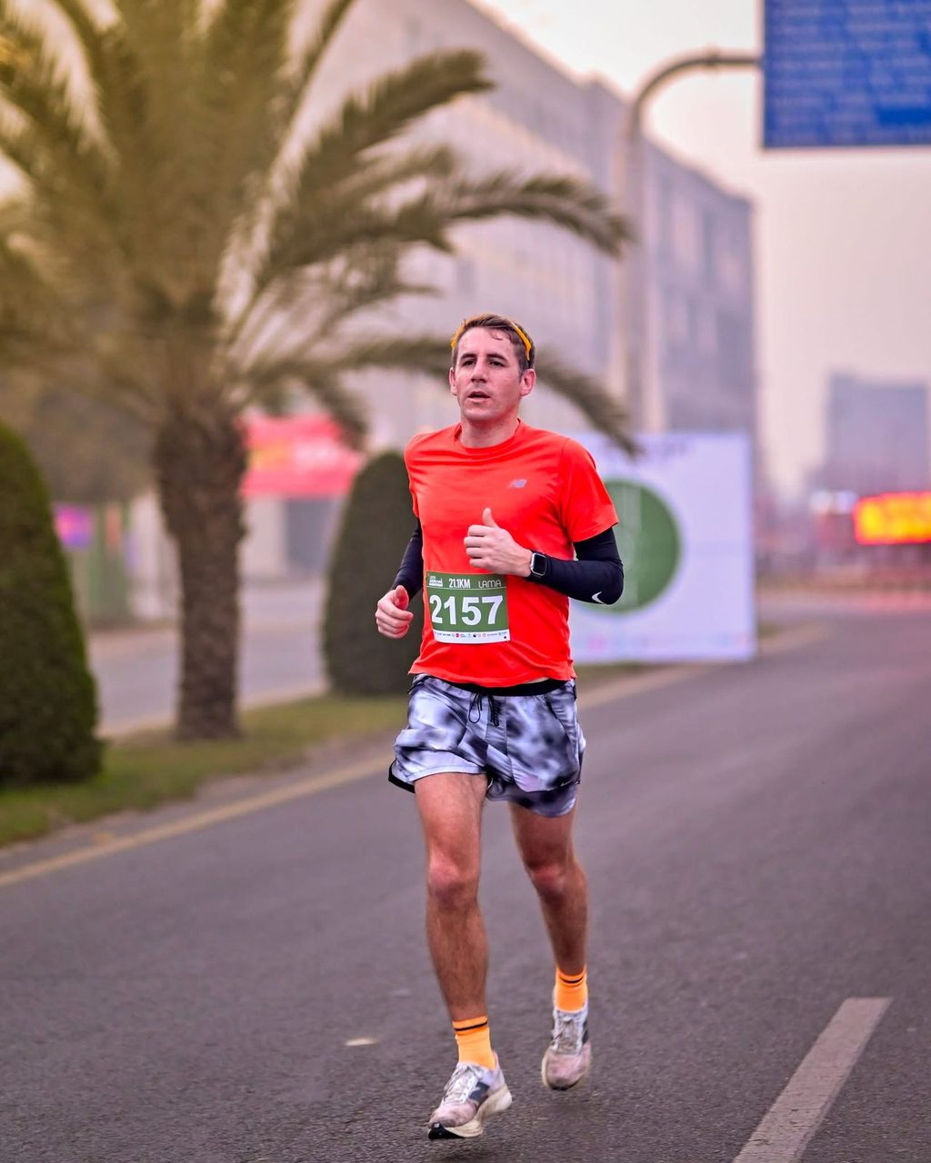 A runner in an orange shirt on a misty morning course