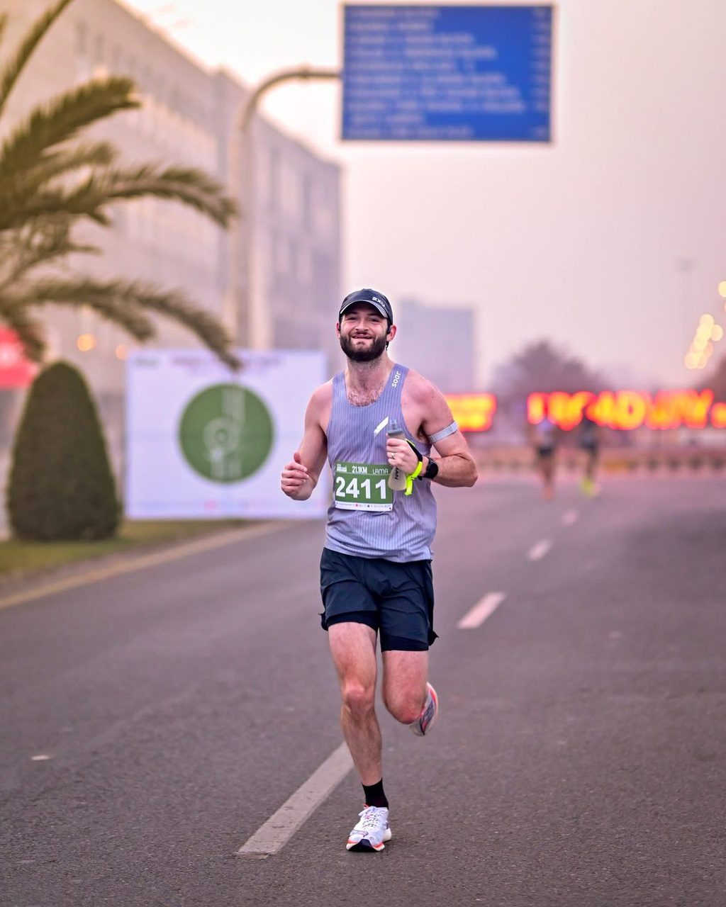 A bearded runner in a grey vest smiling at the camera