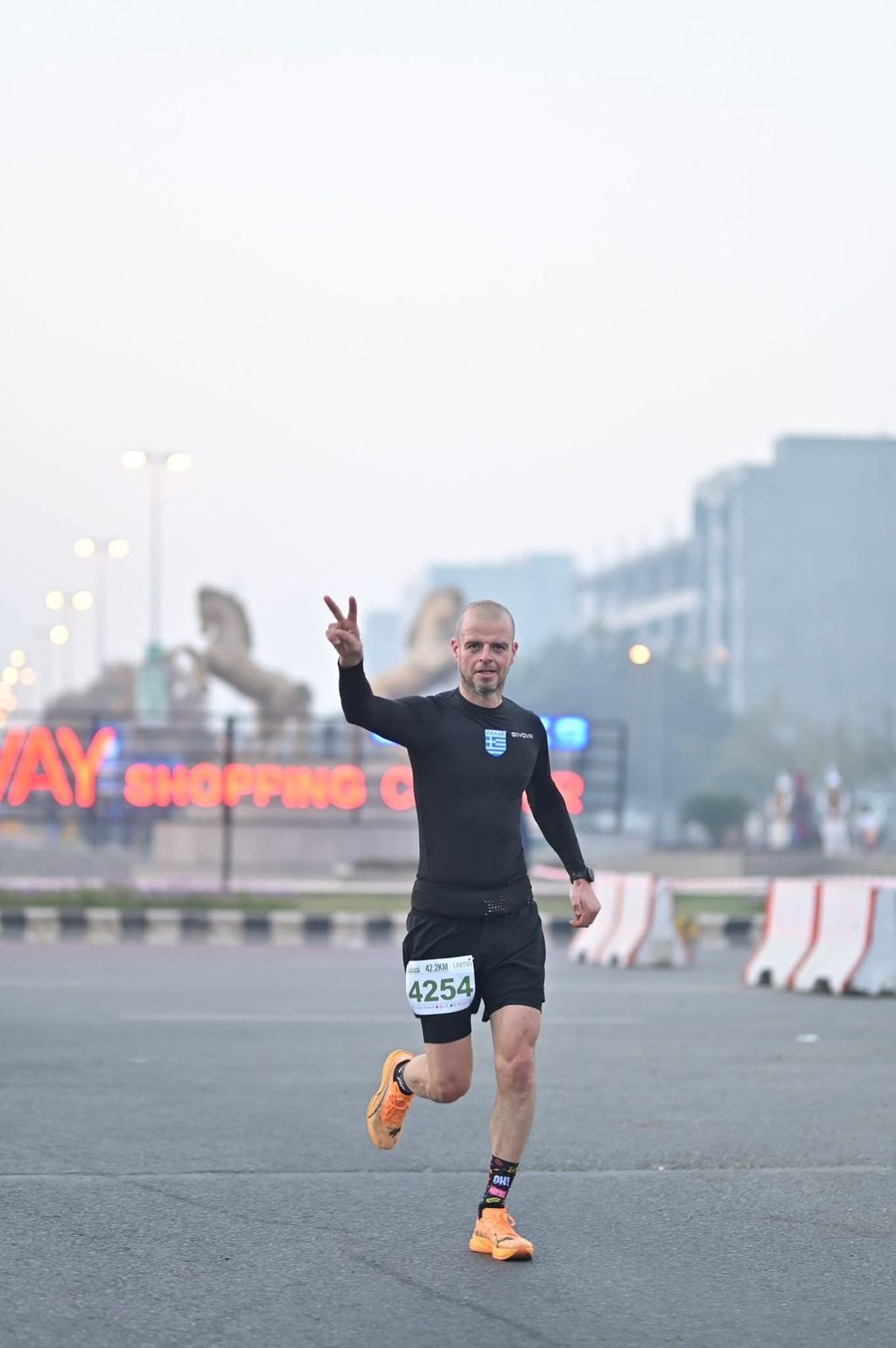 A runner in black making a peace sign on the course