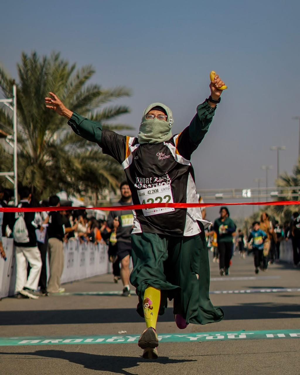 A woman raising her arms as she breaks the finish tape